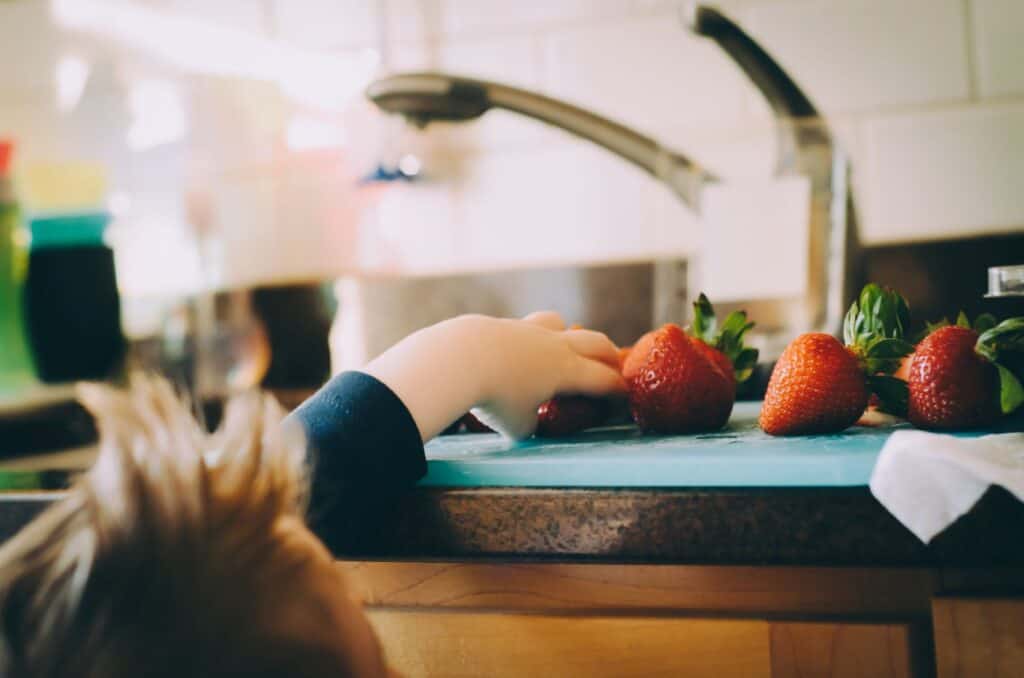 child reaching for strawberry, real food kids