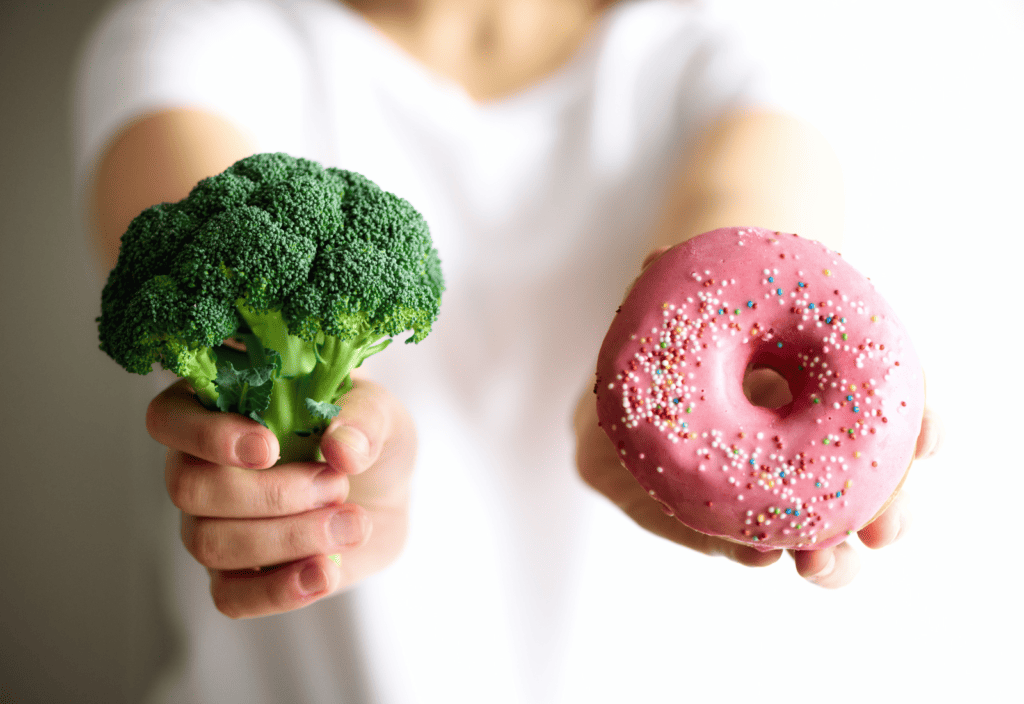 woman holding broccoli and a donut